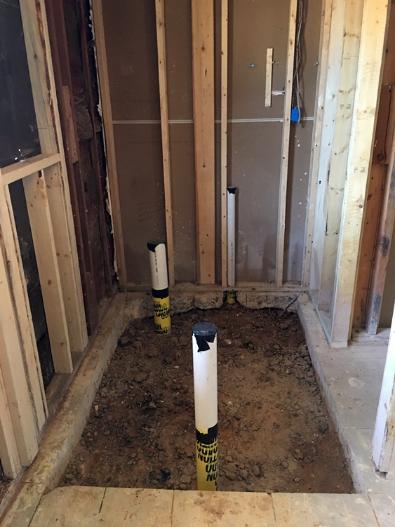 Drain pipes sprouting from hole in concrete