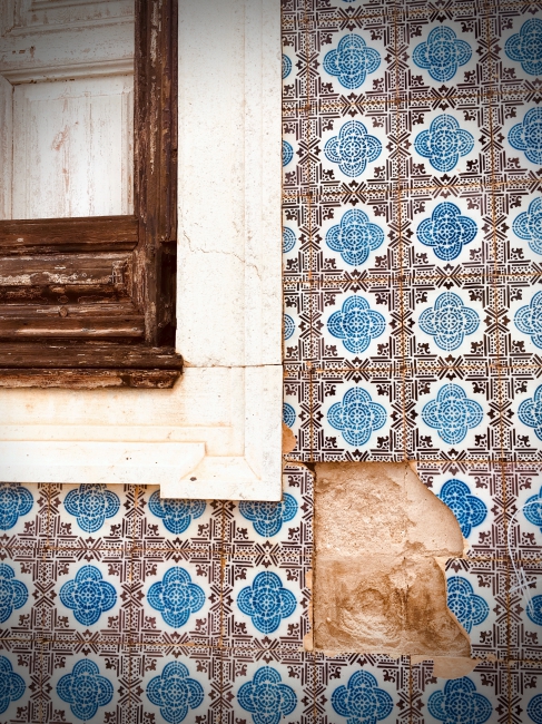 Missing tiles from black and blue tiled wall